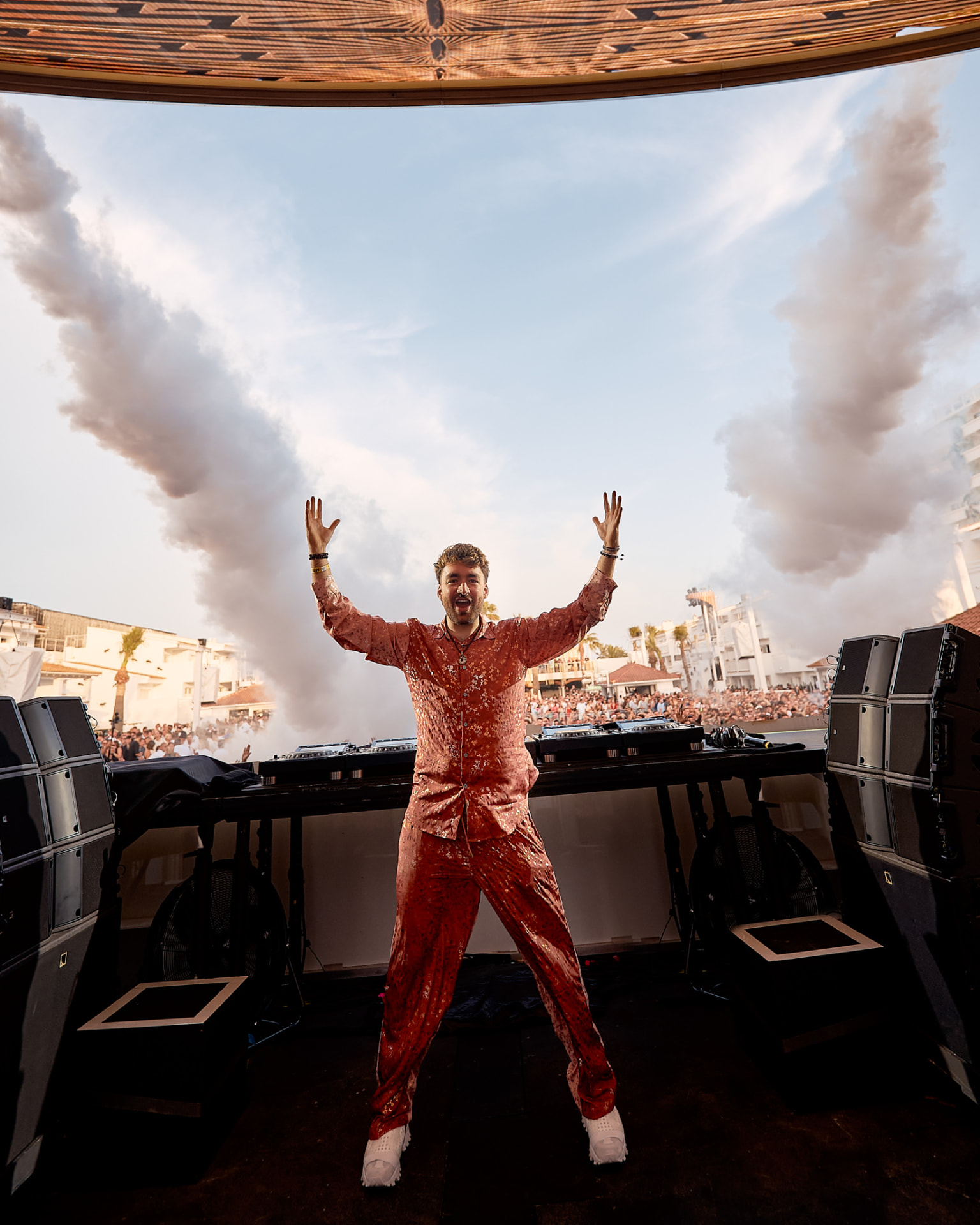 Oliver Heldens na pódiu s bílým kouřem a vztyčenýma rukama